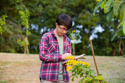 Woman holding umbrella while standing against plants