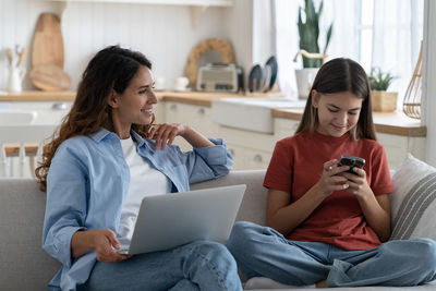 Young friends using phone while sitting at home