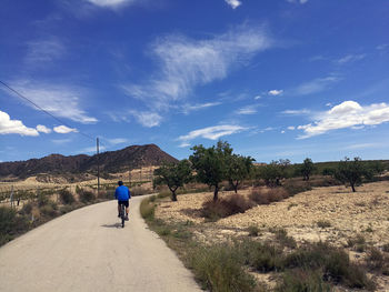 Rear view of man riding motorcycle on road against sky