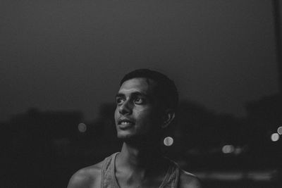 Young man standing against black background