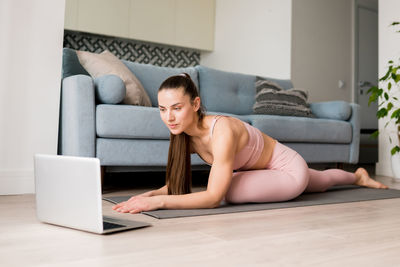 Online yoga classes. woman doing virtual yoga from laptop at home for develop core strength