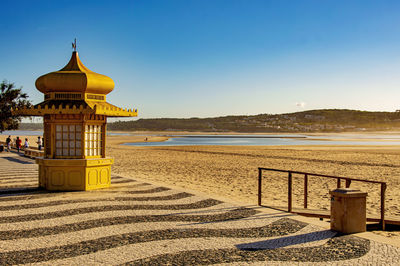 Lifeguard hut on beach against clear blue sky