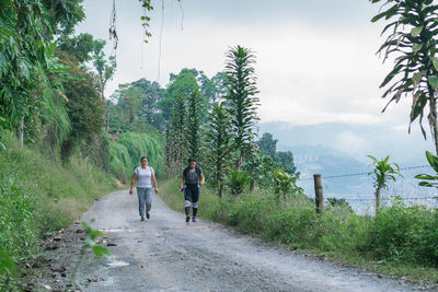 Mother and daughter walking along a dirt road on top of a colombian mountain in the coffee region