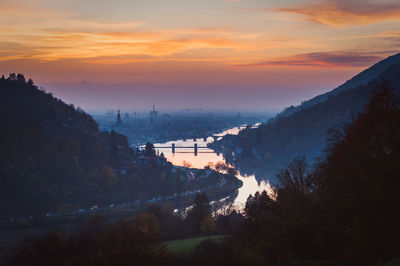 Scenic view of river by mountains against sky during sunset