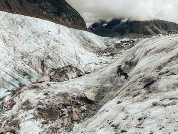 Landscape shot of climber rappelling on glacier under cloudy sky