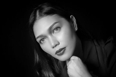 Close-up of young woman against black background