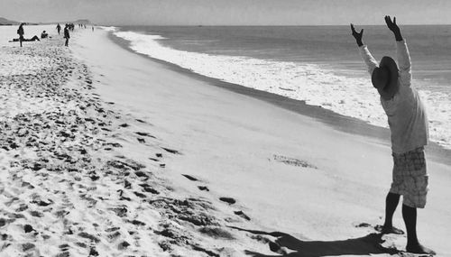 Low section of woman standing on beach against sky