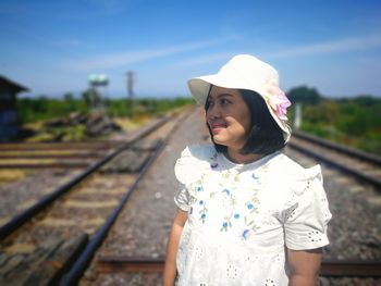 Mid adult woman standing on railroad track against sky