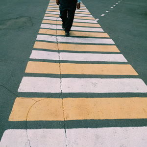 Low section of man walking on zebra crossing