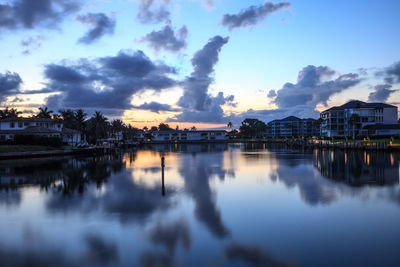 Scenic view of lake by buildings against sky at dusk