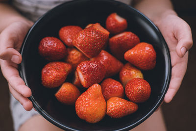 Ripe strawberries in a plate in children's hands. juicy red berries close up.