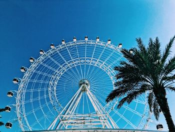 Low angle view of ferris wheel against clear blue sky