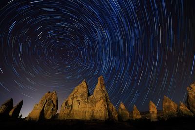 Low angle view of mountains against star trail at night