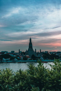 Temple by river during sunset in city