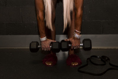 Low section of woman lifting dumbbells in gym