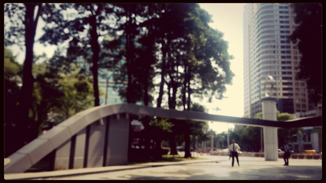 building exterior, architecture, built structure, city, tree, transfer print, street, city life, walking, building, auto post production filter, men, sunlight, incidental people, road, person, day, sky, lifestyles