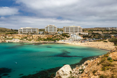 Scenic view of sea by buildings against sky