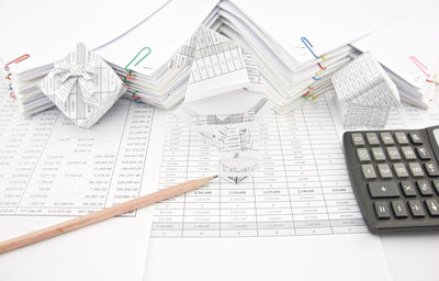 High angle view of calculator and pencil by stacked papers on table