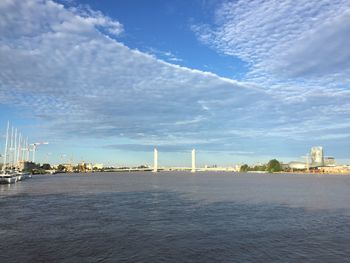 City at waterfront against cloudy sky