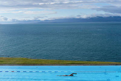 Person swimming in pool against sea