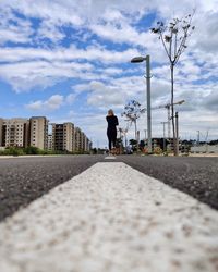 Man walking on street in city against sky