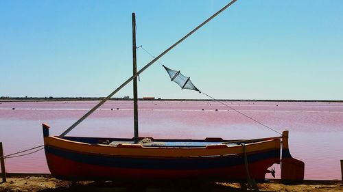 Ship moored on shore against clear sky