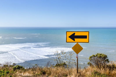 Road sign on beach against clear sky, mendocino ca