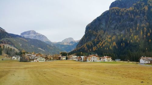 Houses on field by mountains against sky