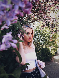 Portrait of young woman against flowering plant