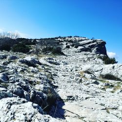 Rocks on land against clear blue sky