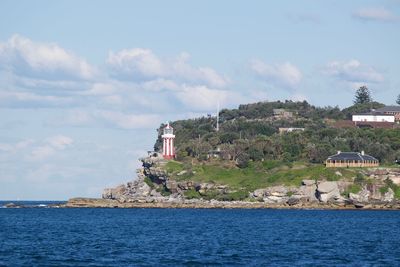 Lighthouse amidst sea and buildings against sky