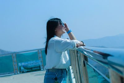 Side view of woman standing by sea against sky