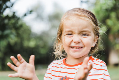 Portrait of cute smiling girl clapping outdoors