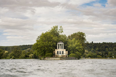 Built structure by river against sky