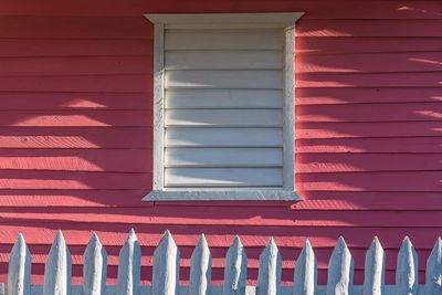 Picket fence against pink wooden house