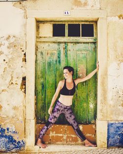 Mid adult woman standing at entrance of old house