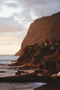 Scenic view of sea by mountains against sky