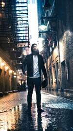 Full length of man standing on cobbled street against illuminated buildings