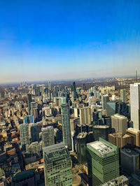 High angle view of modern buildings in city against clear blue sky