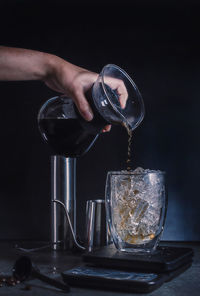 Close-up of hand pouring coffee in glass