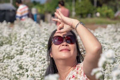 Woman gesturing while wearing sunglasses by flowering plants