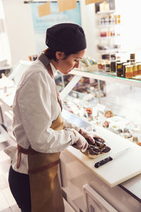 Side view of owner cutting meat at counter in grocery store