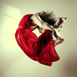  woman in red dress doing a c jump