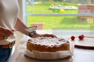 Close-up of hand holding ice cream cone on table