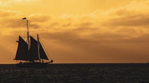 Sailboat sailing on sea against sky during sunset