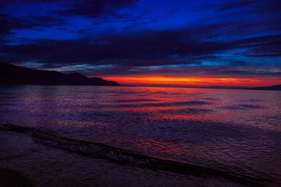 Scenic view of sea against dramatic sky during sunset