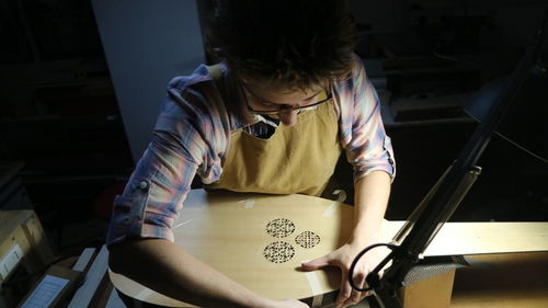 Side view of woman making theorbo 