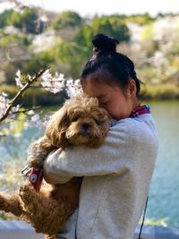 Side view of woman embracing dog by lake