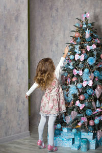 Rear view of girl standing against christmas tree