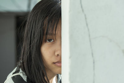 Close-up portrait of woman behind wall